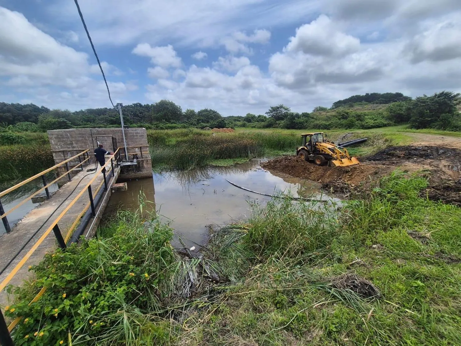 Backhoe loader clearing water infrastructure