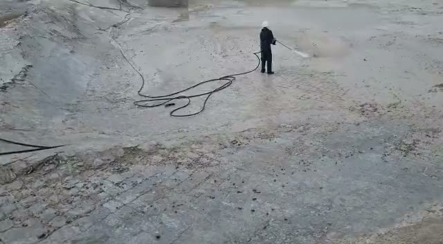 Worker high-pressure cleaning an industrial hardstand